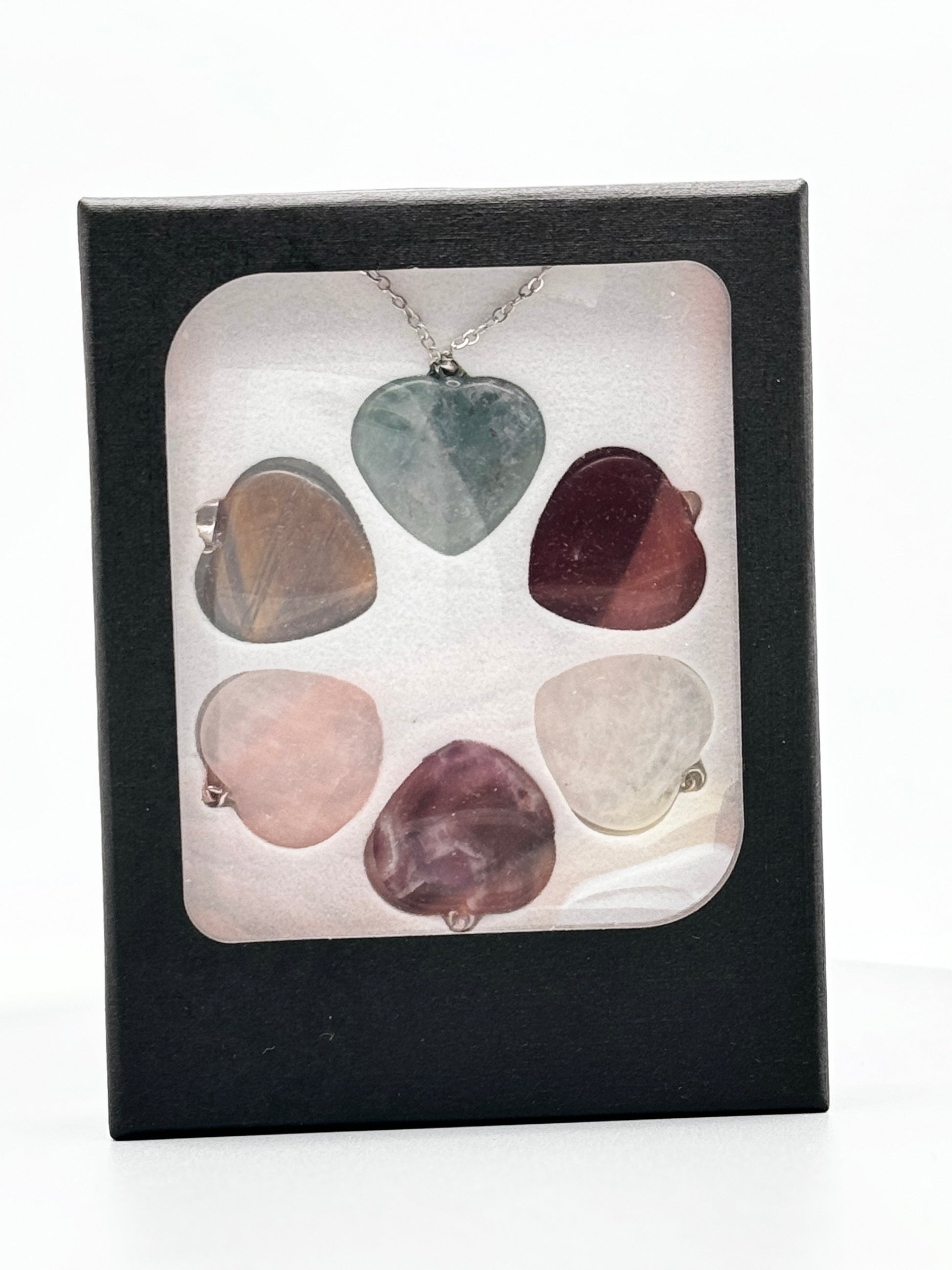 Silberne Kette mit sechs Herz-Anhängern, die mit austauschbaren Kristallen wie Rosenquarz und rotem Jaspis positive Energie verleihen.